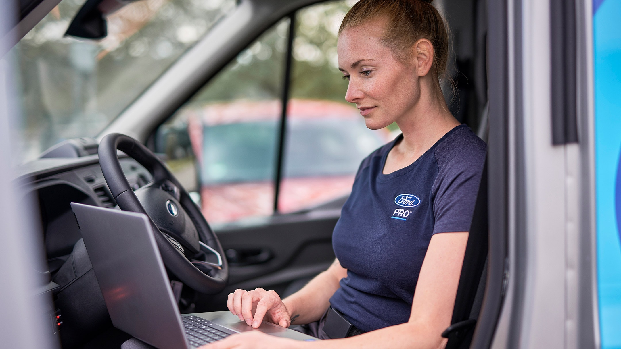Eine Ford Pro Expertin checkt auf ihrem  Laptop während des Ford Services Fahrzeugdaten.