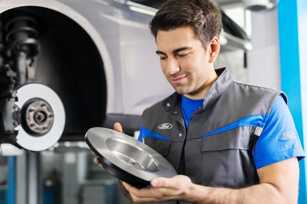Ford Service Werkstatt Mitarbeiter hält Bremsscheiben