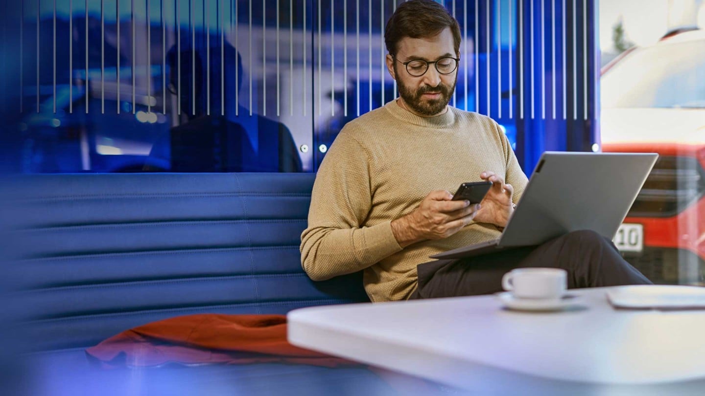 Ein Mann, der an einem Tisch mit einem Laptop und Handy in einem modernen Büro sitzt